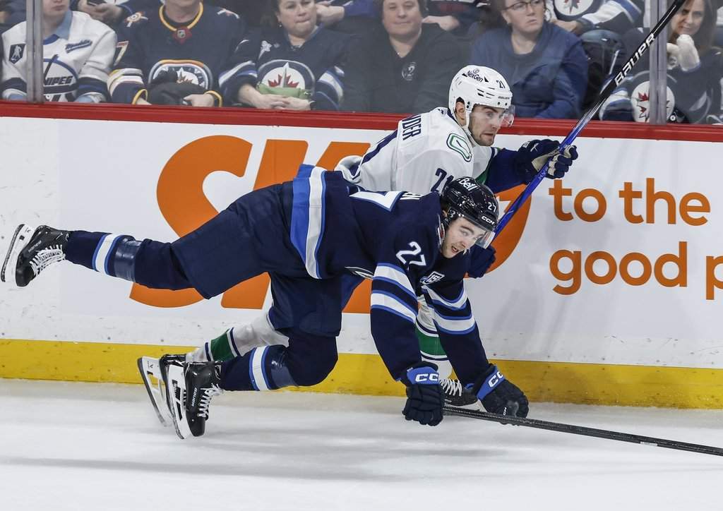 Winnipeg Jets' Isak Rosen (27) and Vancouver Canucks' Nils Hoglander (21) collide during first period NHL action in Winnipeg, Saturday, March 7, 2026. THE CANADIAN PRESS/John Woods.
