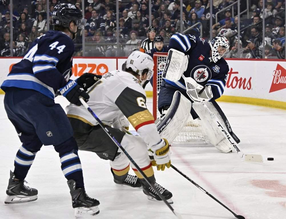 Winnipeg Jets goaltender Connor Hellebuyck (37) clears the puck from behind the net after it was dumped in by he Vegas Golden Knights during the first period of their NHL hockey game in Winnipeg, Tuesday March 24, 2026.