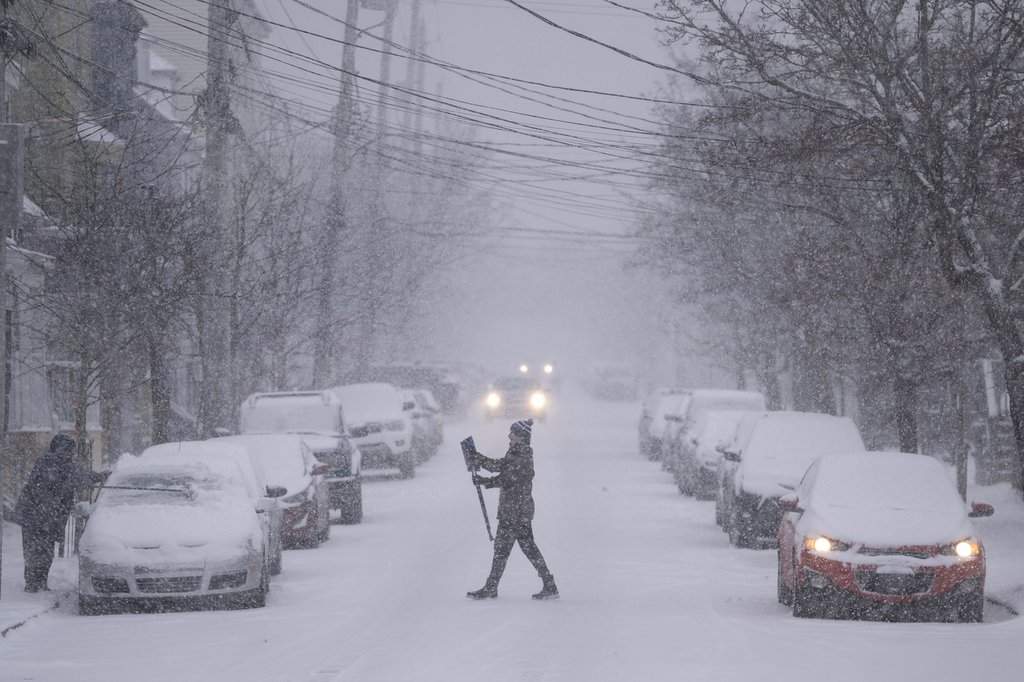 A pedestrian crosses the road with a snow brush as high winds and heavy snow blanket Halifax, Wednesday, Jan. 29, 2025. 