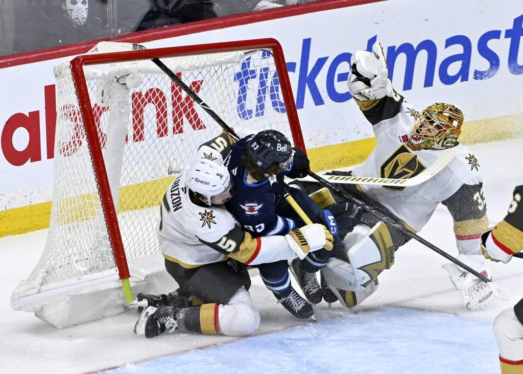 Winnipeg Jets' Brad Lambert (93) collides with Vegas Golden Knights goaltender Adin Hill (33) as Jeremy Lauzon (5) defends during the third period of their NHL hockey game in Winnipeg, Tuesday, March 24, 2026. THE CANADIAN PRESS/Fred Greenslade.