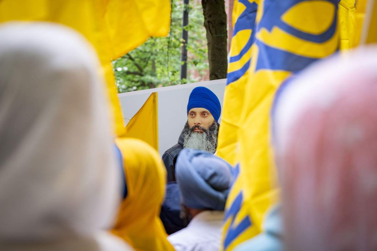 A protester holds a sign with the image of slain Sikh leader Hardeep Singh Nijjar at Indian consulate in Vancouver, June 24, 2023. THE CANADIAN PRESS/Ethan Cairns.