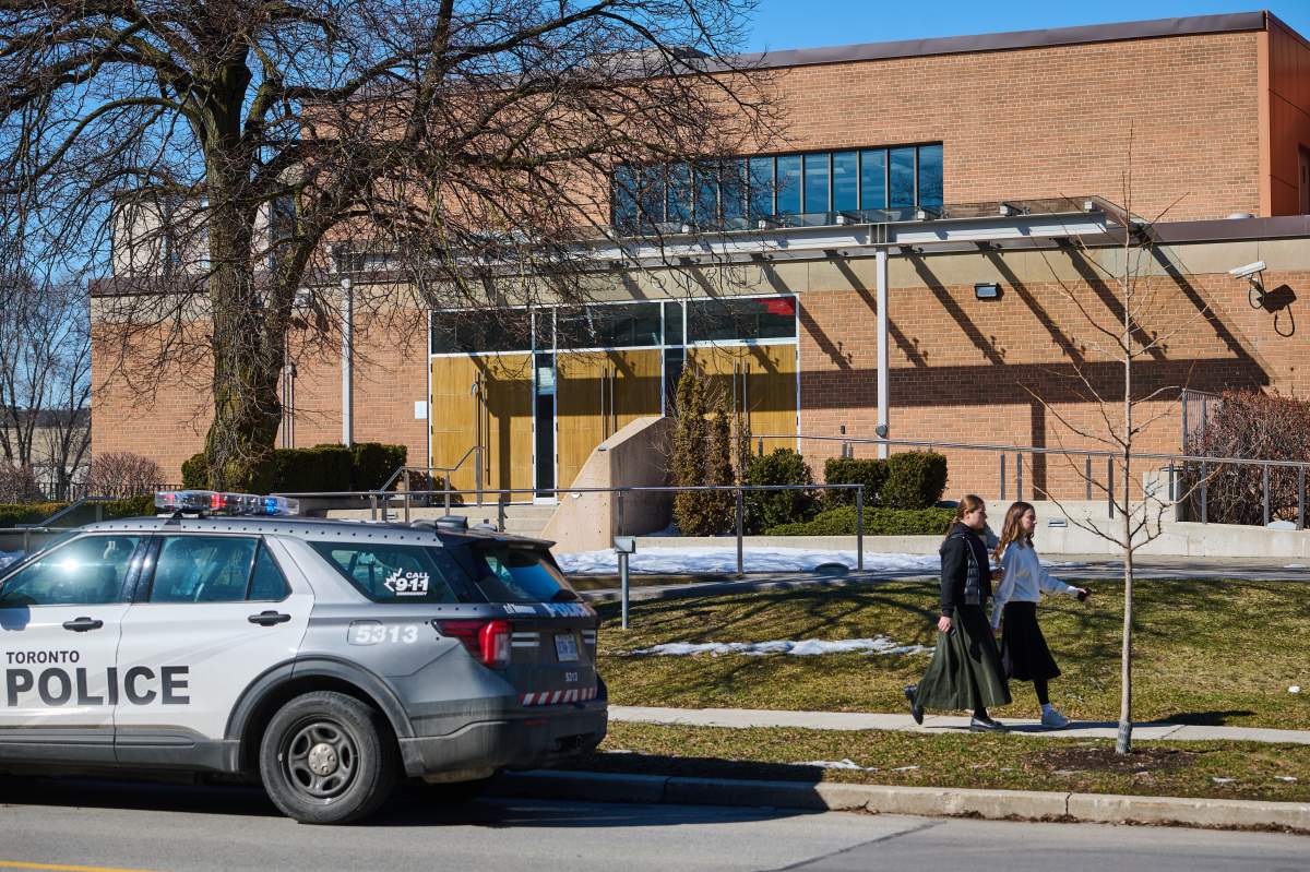 Pedestrians pass by a police car parked outside Shaarei Shomayim synagogue in Toronto, on Sunday, March 8, 2026. The synagogue was struck with gunfire overnight.