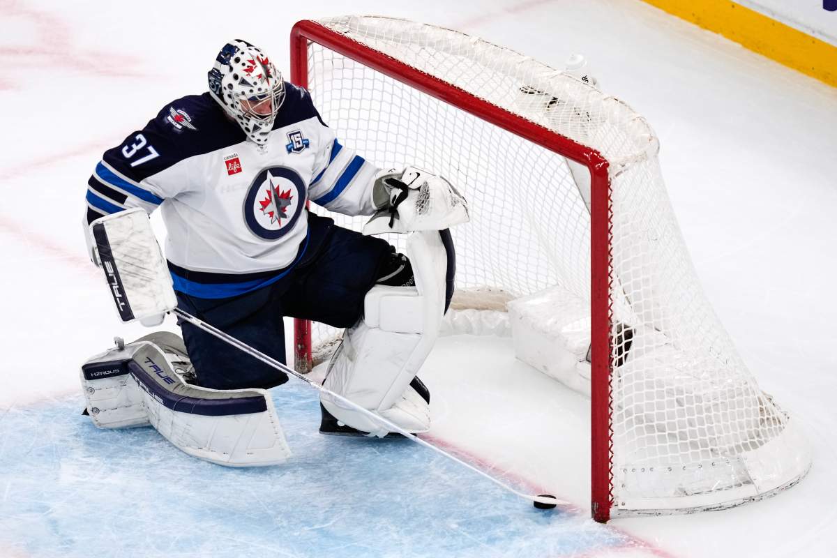 Connor Hellebuyck slides the puck out of the net
