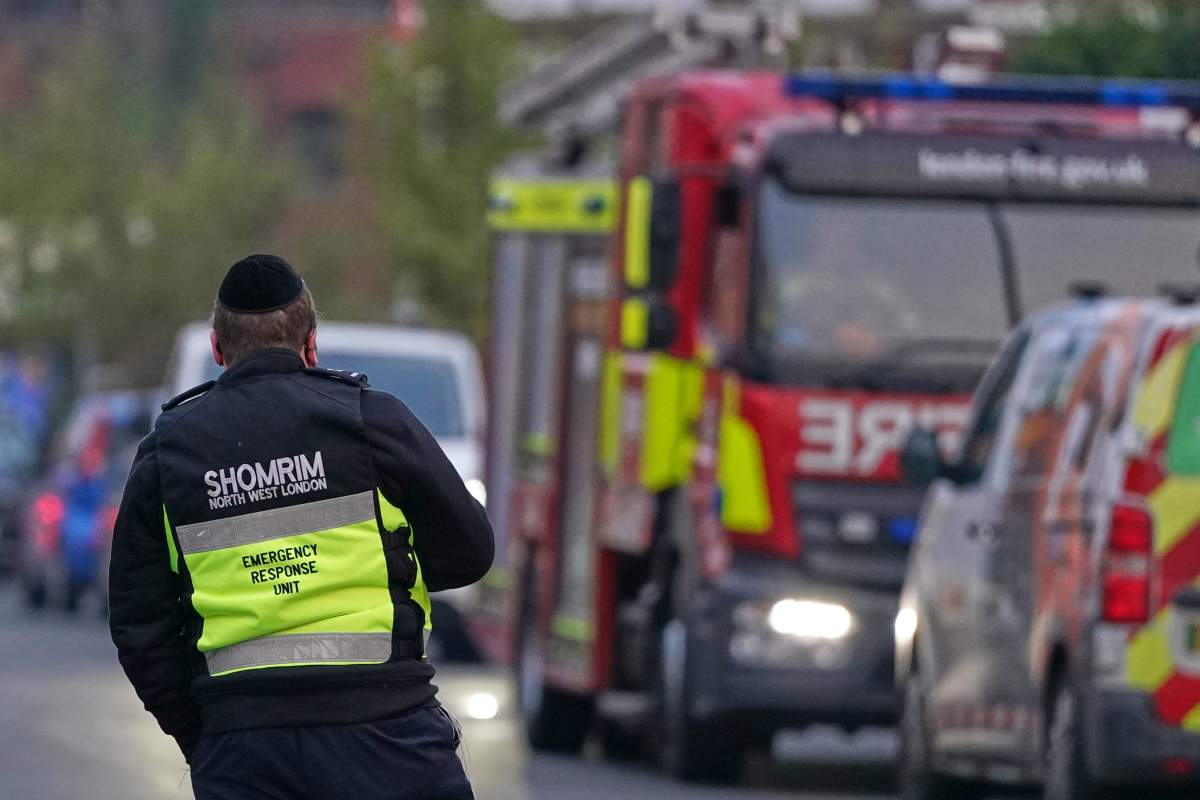 An officer from an emergency response unit watches a firefighter response team in London, Monday, March 23, 2026 after an apparent arson attack on four vehicles belonging to the Jewish ambulance service, Hatzola Northwest, in London.