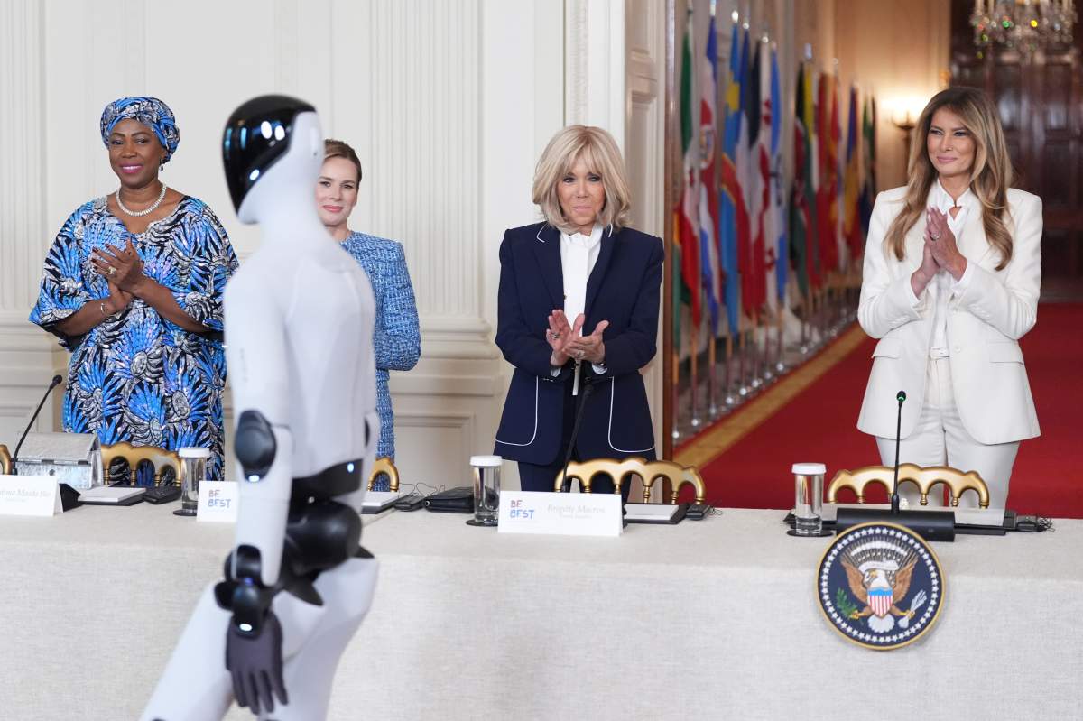 First lady Melania Trump arrives, accompanied by a robot, to attend the "Fostering the Future Together Global Coalition Summit," with other first spouses, at the White House, Wednesday, March 25, 2026, in Washington.