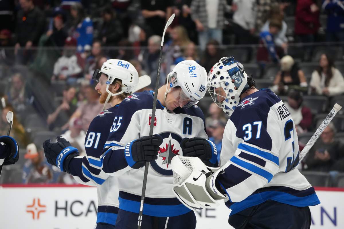 Winnipeg Jets center Mark Scheifele (55) congratulates goaltender Connor Hellebuyck (37) after defeating the Colorado Avalanche in an NHL hockey game Saturday, March 28, 2026, in Denver. (AP Photo/David Zalubowski).