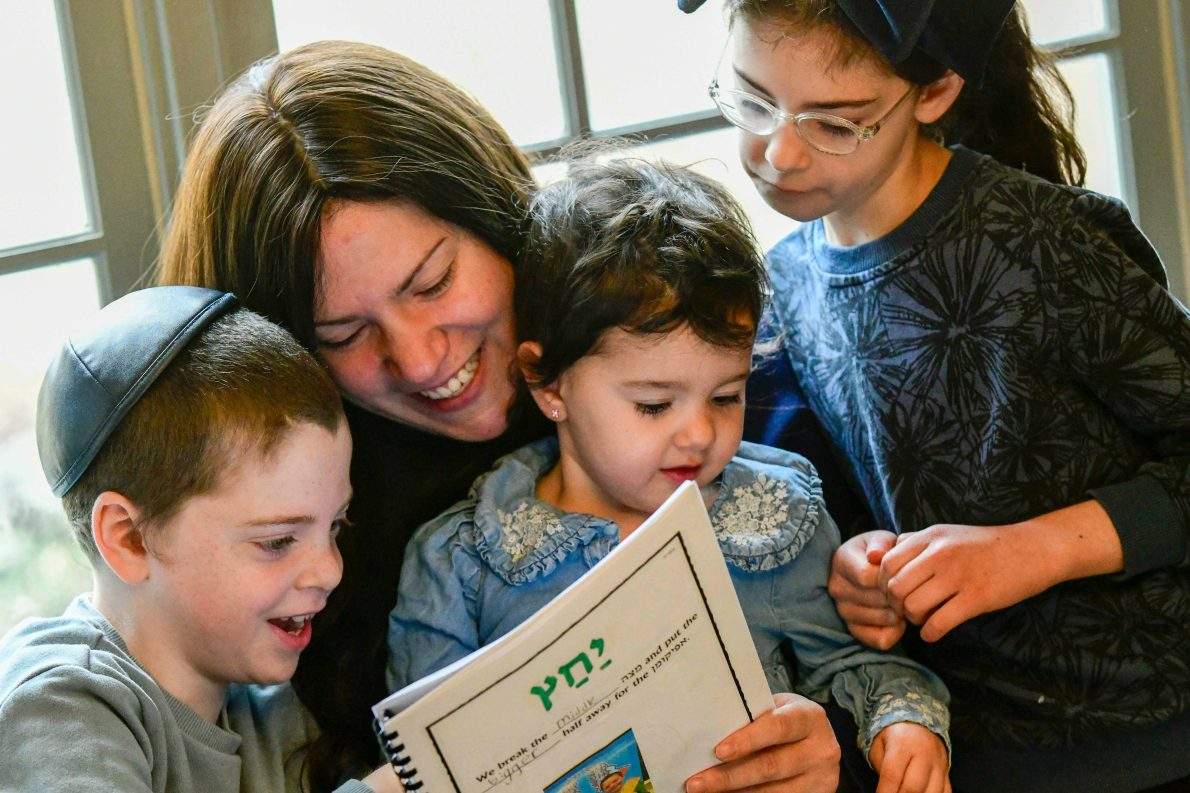 Chaya Raskin of Brattleboro, Vt., is surrounded by her children as she reads the Haggadah, a special book containing the story of the Exodus, prayers, and rituals, on Tuesday, March 31, 2026, ahead of Passover on Wednesday.(Kristopher Radder/The Brattleboro Reformer via AP).