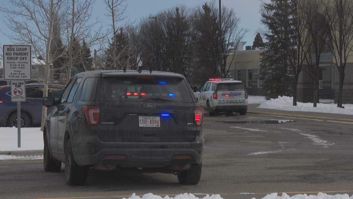 RCMP cars are shown stationed outside the front entrance of Notre Dame Collegiate, in High River, Alta., on Mar. 10 2026. Police evacuated the school after a bomb threat.