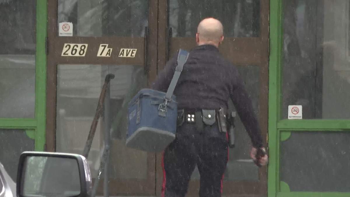 A Lethbridge police officer is seen entering the Garden Villa Apartments on Monday after two men were charged with first degree murder following a fatal assault inside the apartment complex last week.