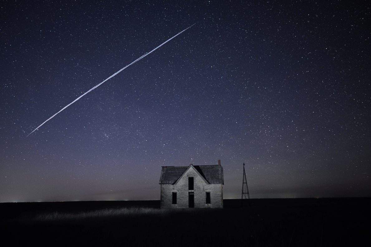 FILE - In this long exposure photo, a string of SpaceX StarLink satellites passes over an old stone house near Florence, Kan., on May 6, 2021. (AP Photo/Reed Hoffmann, File).