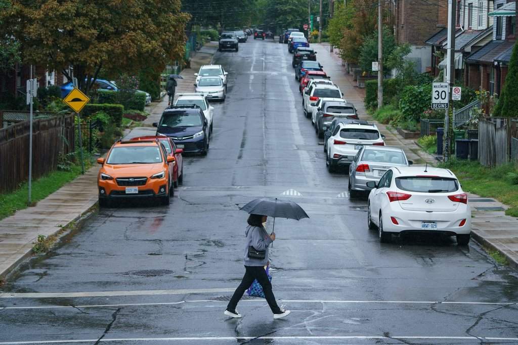 A person carries an umbrella during a downpour of rain in Toronto on Tuesday, Sept. 27, 2022. 