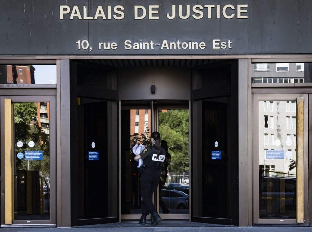 A police officer carries paperwork into the Montreal courthouse in Montreal on Monday, Aug. 18, 2025. THE CANADIAN PRESS/Christinne Muschi.
