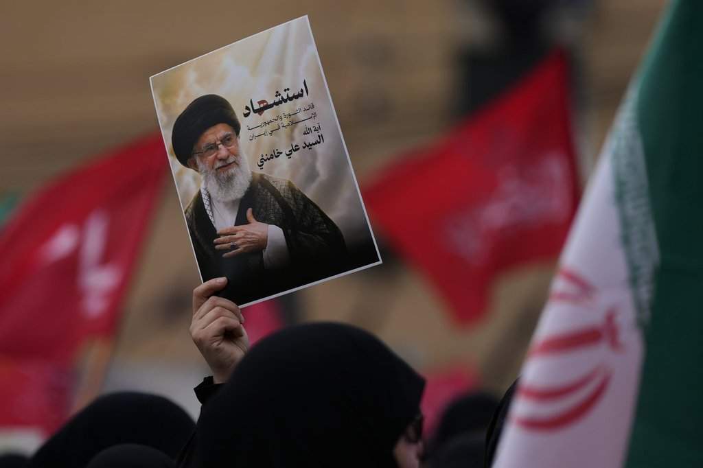 A Hezbollah supporter holds up a portrait of the late Iranian Supreme Leader Ayatollah Ali Khamenei during a gathering in the southern suburbs of Beirut, Lebanon, Sunday, March 1, 2026. The Arabic words on the portrait read:"Martyrdom of the leader of the Islamic revolution in Iran, sayyed Ayatollah Ali Khamenei." (AP Photo/Hassan Ammar).