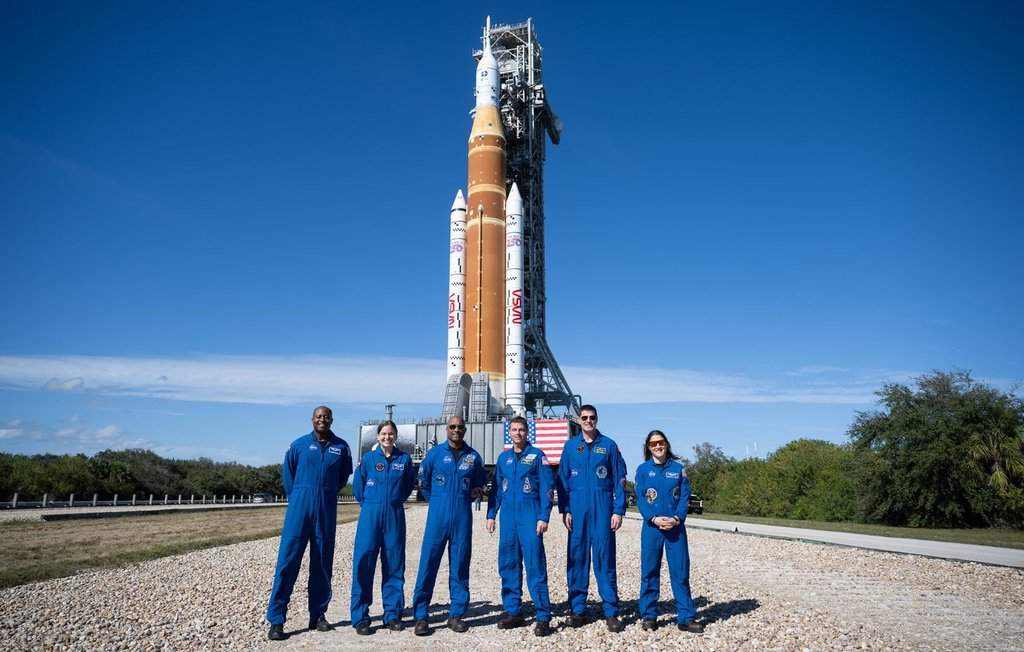 Artemis II backup crewmembers NASA astronaut Andre Douglas, left to right, and Canadian Space Agency astronaut Jenni Gibbons pose for a group photo with prime crewmembers NASA astronauts Victor Glover, Reid Wiseman, CSA astronaut Jeremy Hansen, and NASA astronaut Christina Koch, in front of NASA’s Space Launch System (SLS) rocket and Orion spacecraft, secured to the mobile launcher, as it makes the 4.2 mile journey from the Vehicle Assembly Building to Launch Pad 39B at NASA’s Kennedy Space Center in Cape Canaveral, Fla., in a Saturday, Jan. 17, 2026, handout photo.