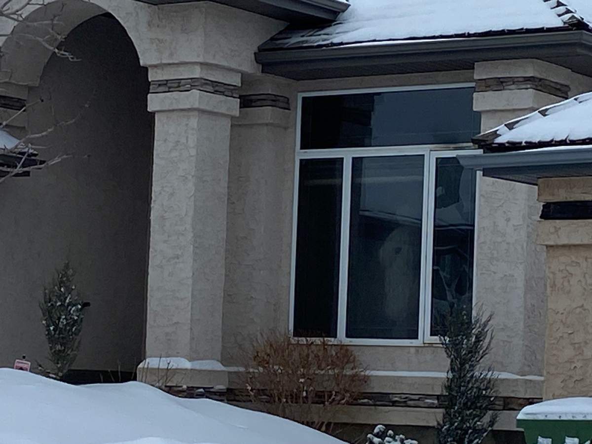 Members of what appears to be a damage restoration crew are seen Wednesday through the window of a home where a woman's body was found following a fire on Feb. 19.