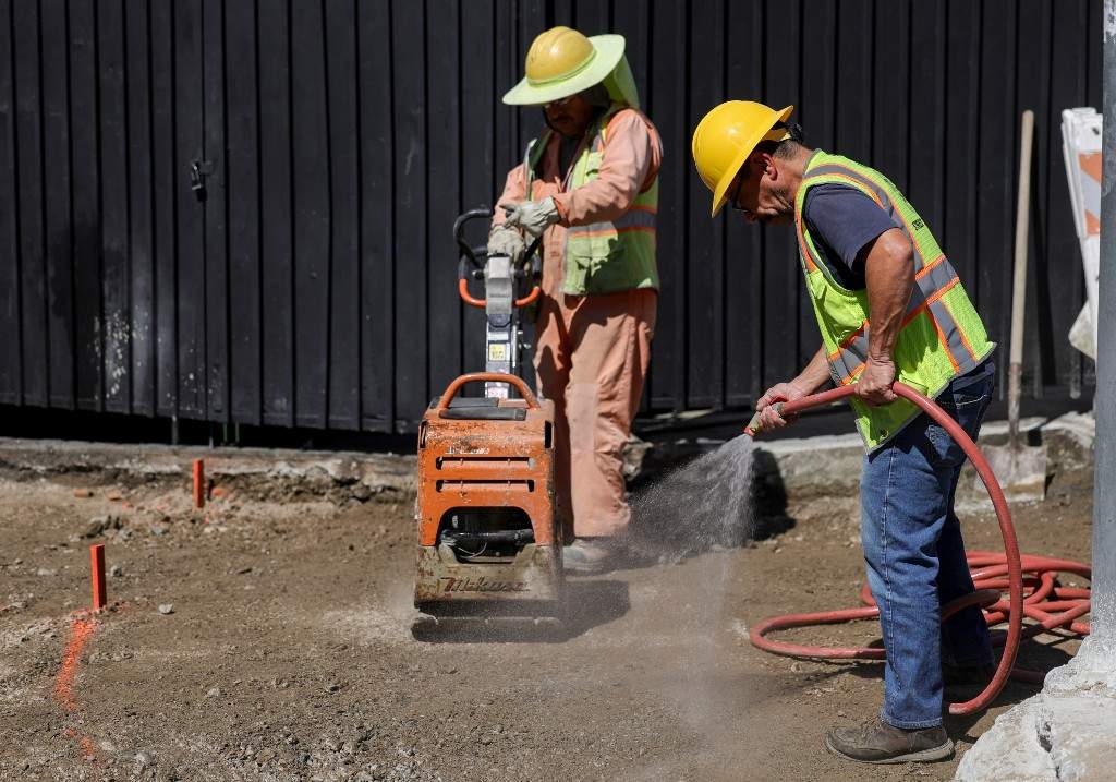 Construction workers spray water during an unseasonably hot day at MacArthur Park on Thursday, Mar. 12, 2026 in Los Angeles.