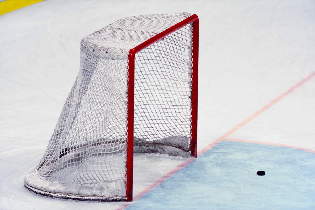 A hockey puck sits inches from the net.