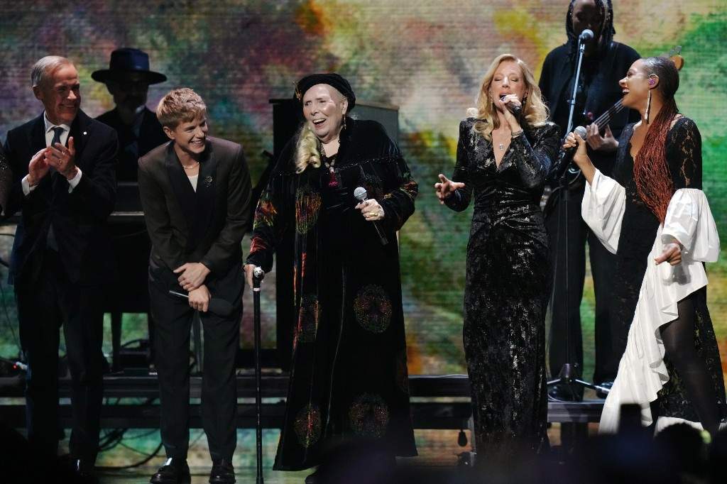 Joni Mitchell, centre, performs with Sarah McLachlan, second right, and Allison Russell, right, as Prime Minister Mark Carney, left, and host Mae Martin look on at the 2026 Juno Awards in Hamilton, on Sunday, March 29, 2026.