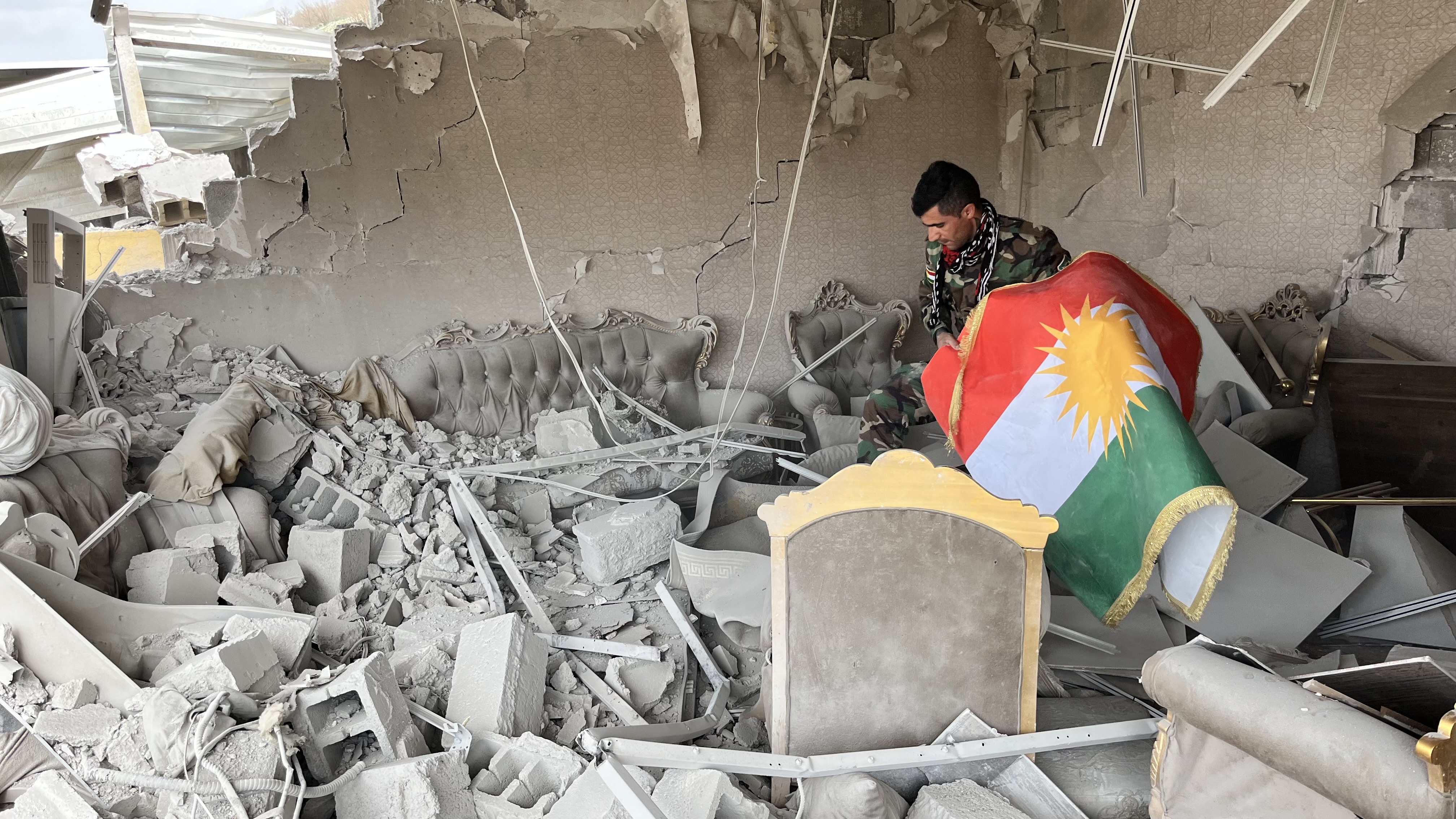 Iranian Kurdish fighter carries flag at base bombed by Iran, Degala, Iraq, March 7, 2026.