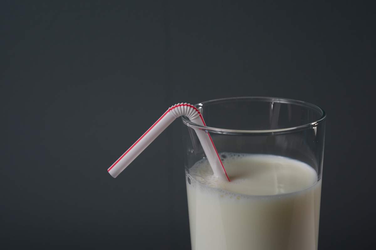 A plastic straw sits in a glass of milk.