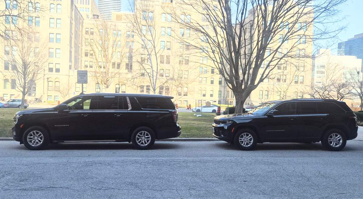 A Chevrolet Suburban (left) with three rows of seats parked in front of a two-row Jeep Cherokee at Queen’s Park