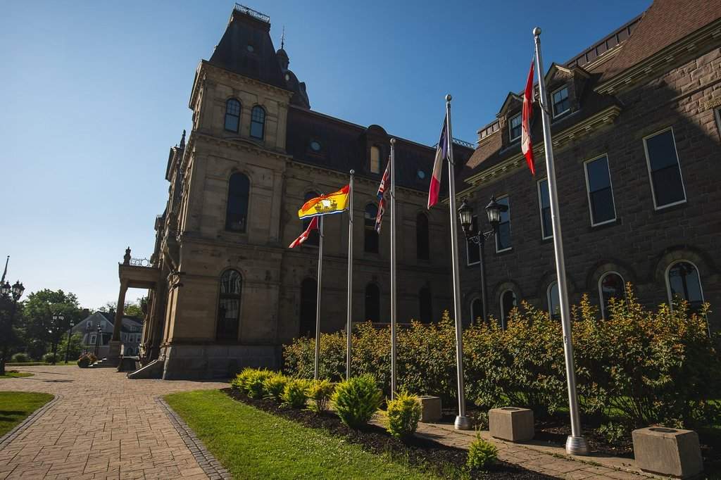 The New Brunswick flag flies in a row of flags beside the Legislative Assembly Building, home of the provincial parliament, in Fredericton, Saturday, July 26, 2025. THE CANADIAN PRESS/Giordano Ciampini.