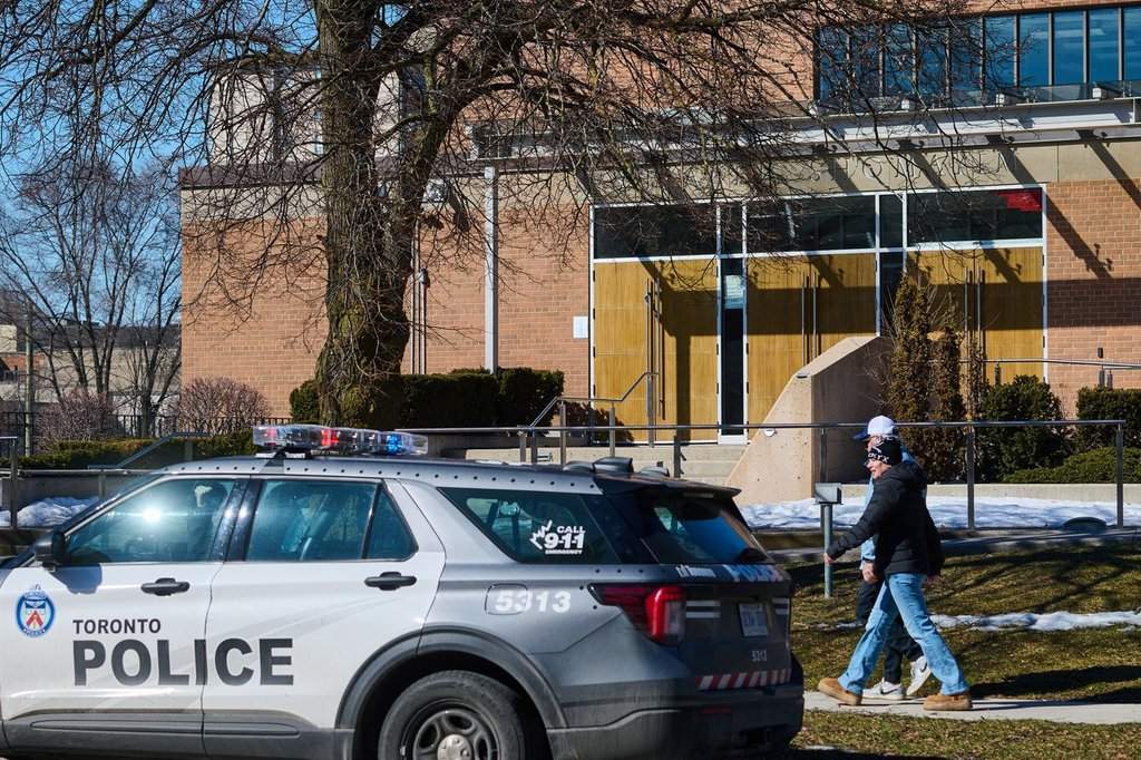 Pedestrians pass by a police car parked outside Shaarei Shomayim synagogue in Toronto, on Sunday, March 8, 2026. 