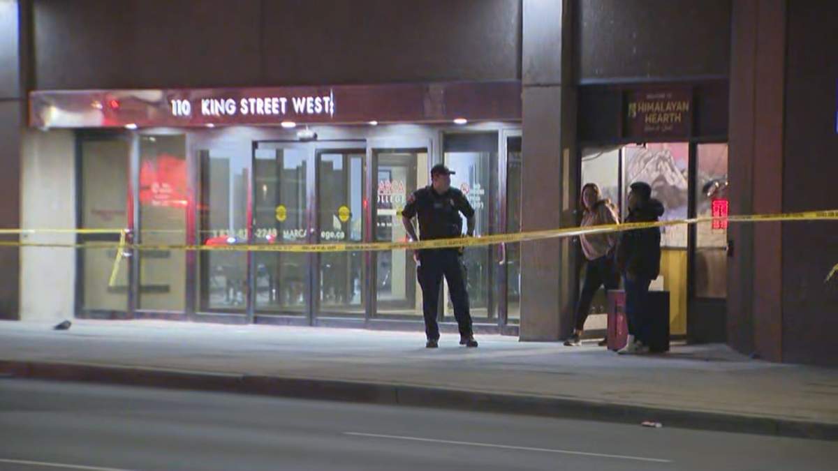 Police officer stands behind police tape infront of glass mall doors