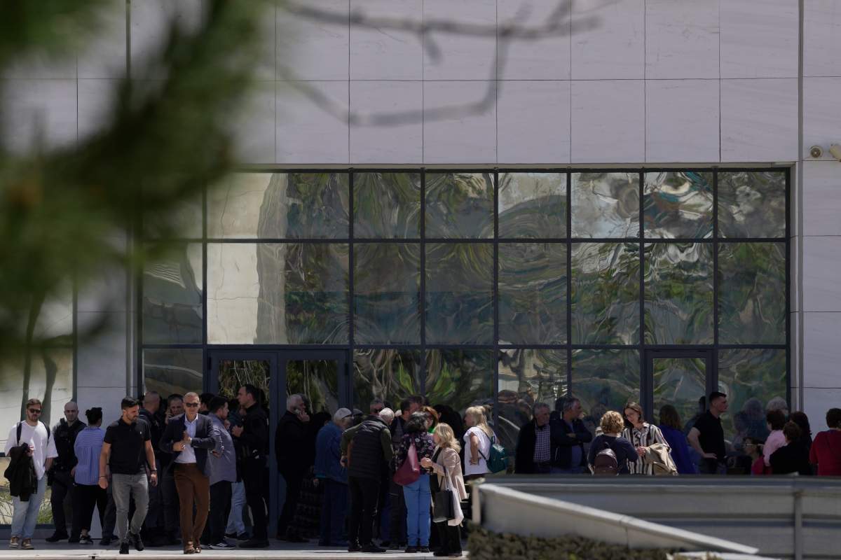 FILE– People gather outside a courthouse after a gunman opened fire leaving several people wounded in Athens, Tuesday, April 28, 2026.