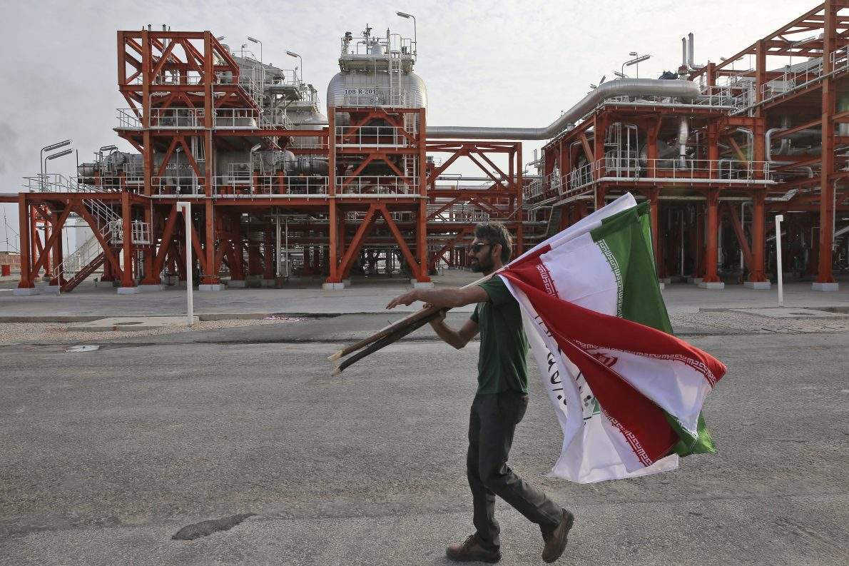FILE - In this Saturday, March 16, 2019 photo, an Iranian worker carries Iranian flags prior to an inauguration ceremony of a natural gas refinery at the South Pars gas field on the northern coast of the Persian Gulf, in Asaluyeh, Iran.