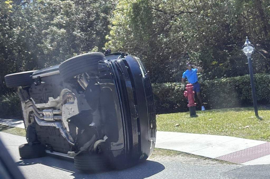 Golfer Tiger Woods stands by his overturned vehicle in Jupiter Island, Fla., March 27, 2026.