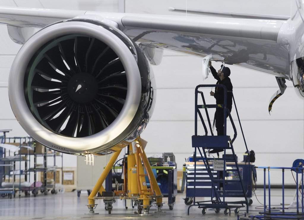 An Airbus employee works under the wing of an Airbus A220 at the assembly plant in Mirabel, Que., Thursday, Feb. 20, 2020. THE CANADIAN PRESS/Graham Hughes.