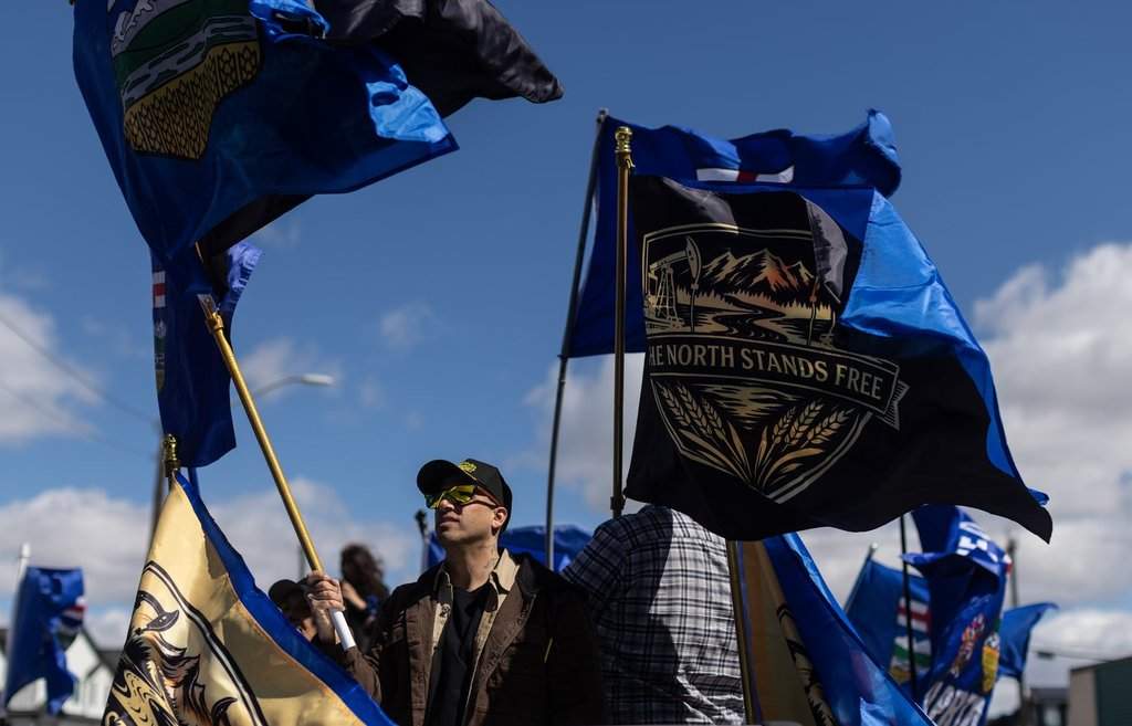 Supporters fly flags in support of Mitch Sylvestre as he submits his signatures for a separation referendum to Elections Alberta in Edmonton, on Monday, May 4, 2026. 