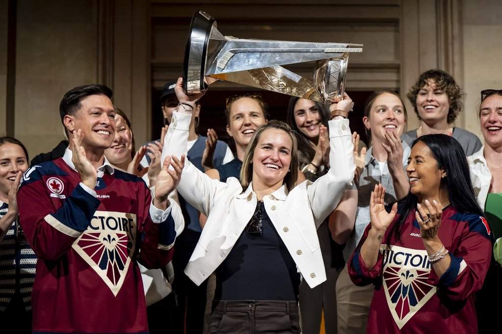 Montreal Victoire’s Marie-Philip Poulin hoists the Walter Cup while surrounded by teammates and flanked by Montreal Mayor Soraya Martinez Ferrada, right, and Laval Mayor Stéphane Boyer, at Montreal City Hall following the PWHL team’s Walter Cup victory, in Montreal on Tuesday, May 26, 2026.