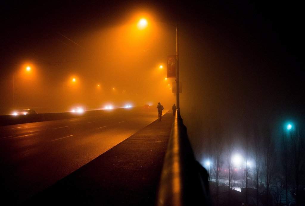 Two men are silhouetted while walking across the Granville Street Bridge as dense fog fills the air in Vancouver, B.C., on Saturday Jan. 2, 2016.
