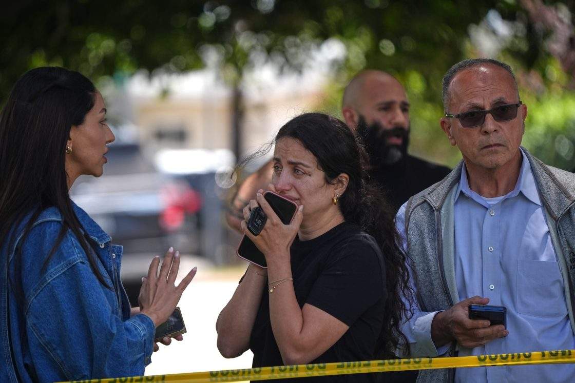 People stand behind police tape at the scene of a shooting outside the Islamic Center of San Diego Monday, May 18, 2026, in San Diego.