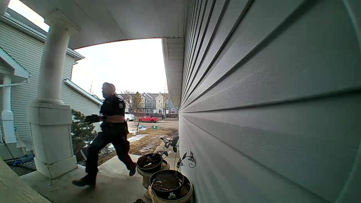 An Edmonton police officer running into the home in south Edmonton’s Summerside neighbourhood where Kache Grist was killed by two dogs in April 2024.