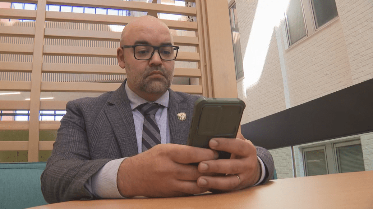 Political scientist Jared Wesley looks at his cellphone