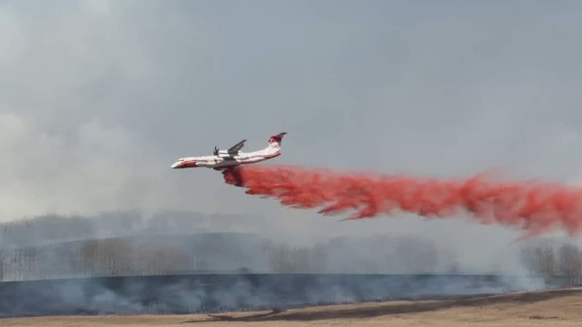 A water bomber is seen dumping a load of retardant on a wildfire that broke out near Ghost Lake, west of Calgary on Thursday.