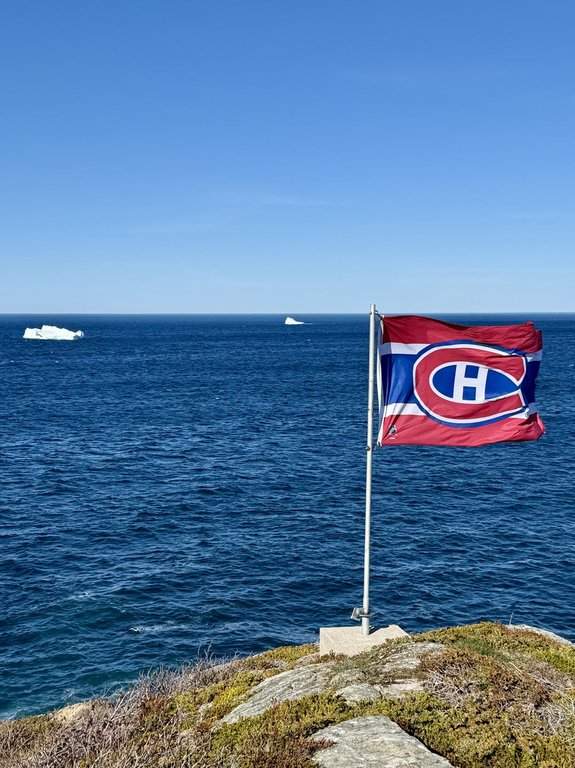 An iceberg is shown floating by Scott LeShane's Montreal Canadiens flag in Lower Island Cove, N.L., on Monday, May 18, 2026. 