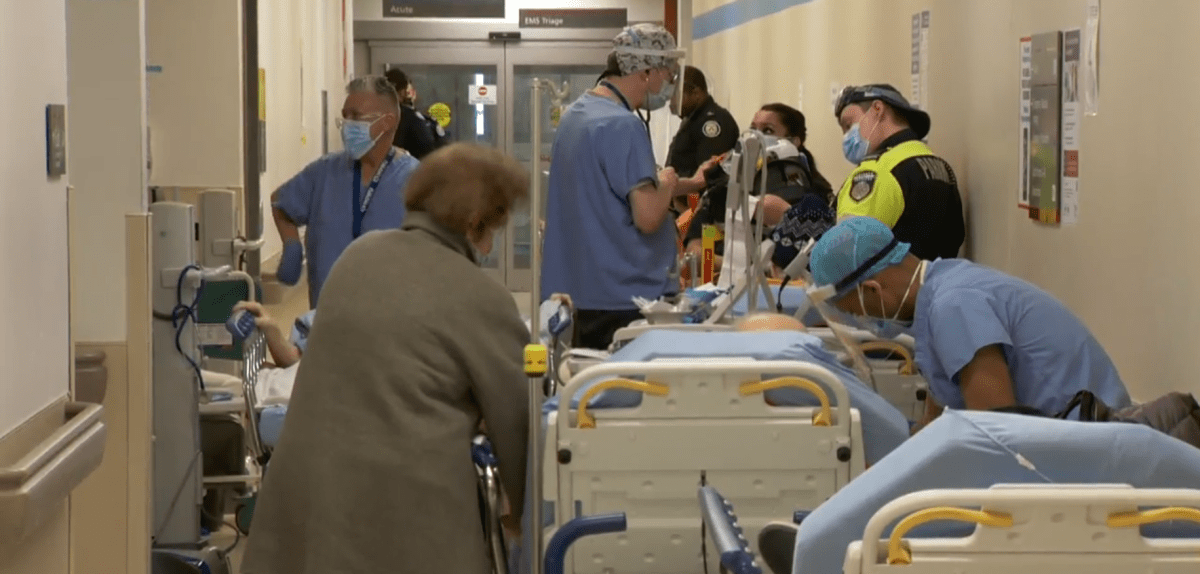 Hospital hallway filled with beds and first responders.