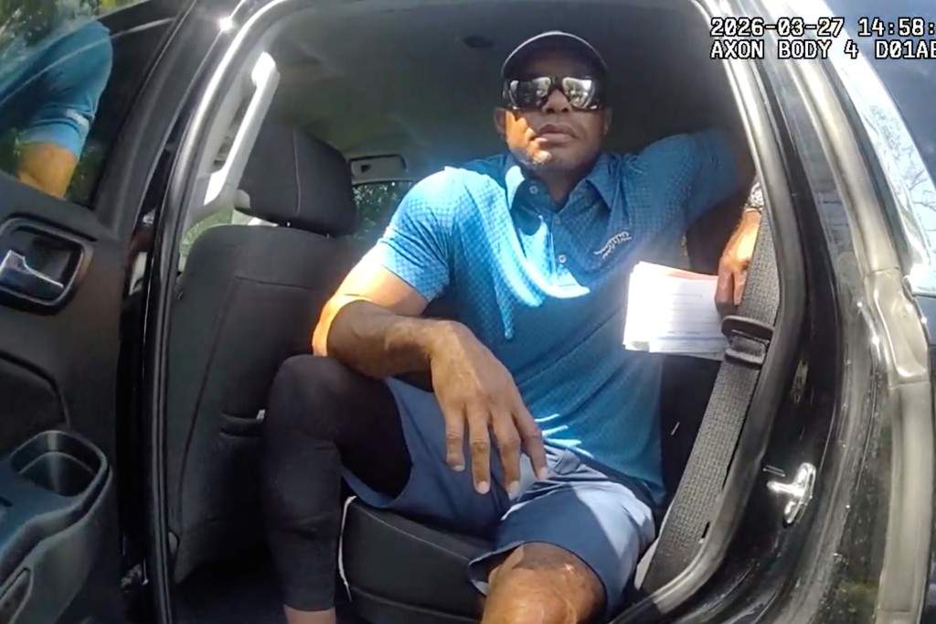 In this image from police body camera video released by the Martin County, Fla., Sheriff's Office, golfer Tiger Woods sits in an unmarked police vehicle as he speaks with law enforcement personnel following a car crash in Jupiter Island, Fla., March 27, 2026.
