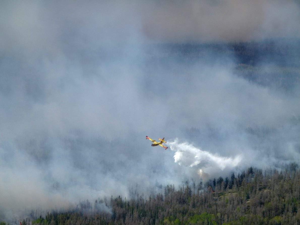 FILE- A water bomber aircraft battles a wildfire in southeast Manitoba as shown in this handout photo provided by the Manitoba government. More people in northern Manitoba were told to leave their homes Saturday as wildfires continued to threaten communities and send thick smoke into the air. THE CANADIAN PRESS/Manitoba government handout.