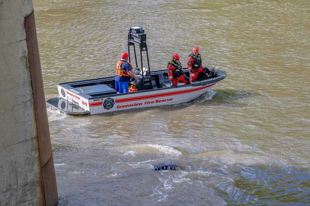 An emergency crew searches the water under the Wapiti River Bridge after a commercial crane drove off the bridge and went into the water, near Grande Prairie, Alta., on Tuesday, June 16, 2026.