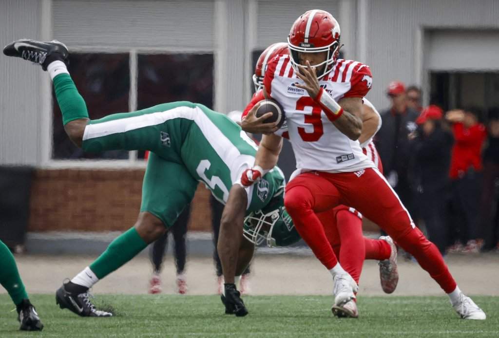 Saskatchewan Roughriders' Justin Weaver, left, dives for Calgary Stampeders quarterback Vernon Adams Jr. during first half pre-season CFL football action in Calgary, Monday, May 18, 2026. THE CANADIAN PRESS/Jeff McIntosh.