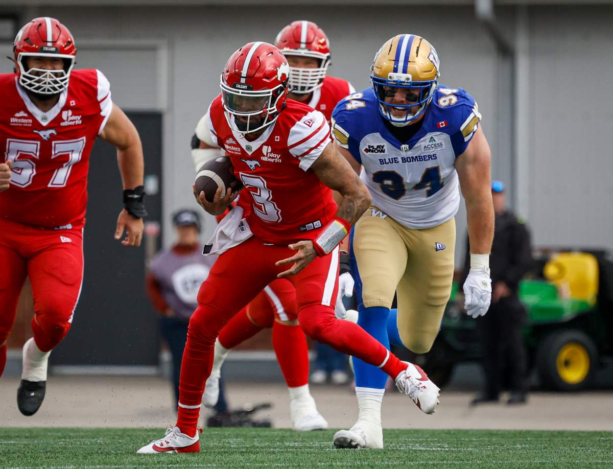 Winnipeg Blue Bombers' Jake Ceresna, right, looks on as Calgary Stampeders quarterback Vernon Adams Jr. runs the football during first half CFL football action in Calgary, Friday, June 5, 2026.THE CANADIAN PRESS/Jeff McIntosh.
