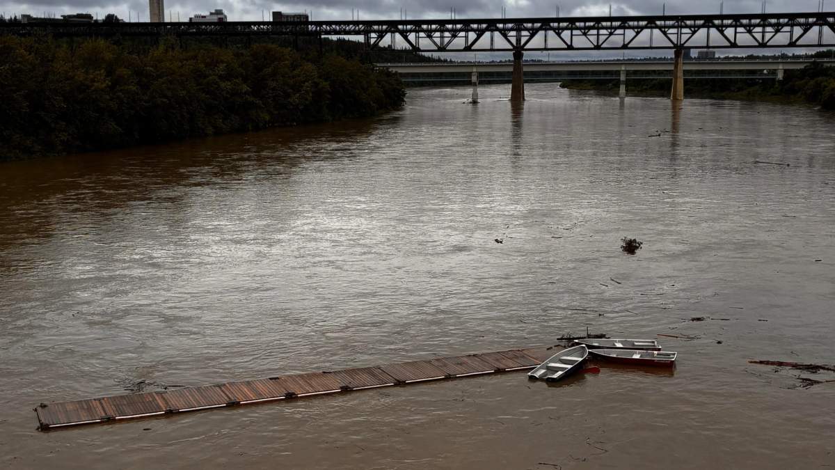 A dock with five boats attached, seen floating down the North Saskatchewan River in Edmonton, Alta. on Monday, June 22, 2026.