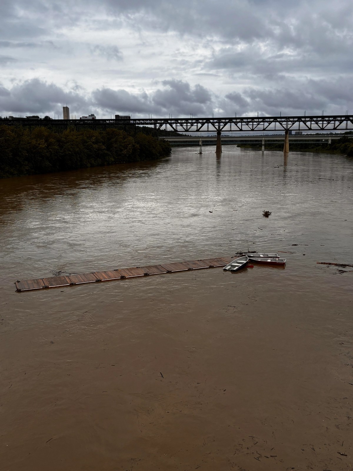 A dock with five boats attached, seen floating down the North Saskatchewan River in Edmonton, Alta. on Monday, June 22, 2026.