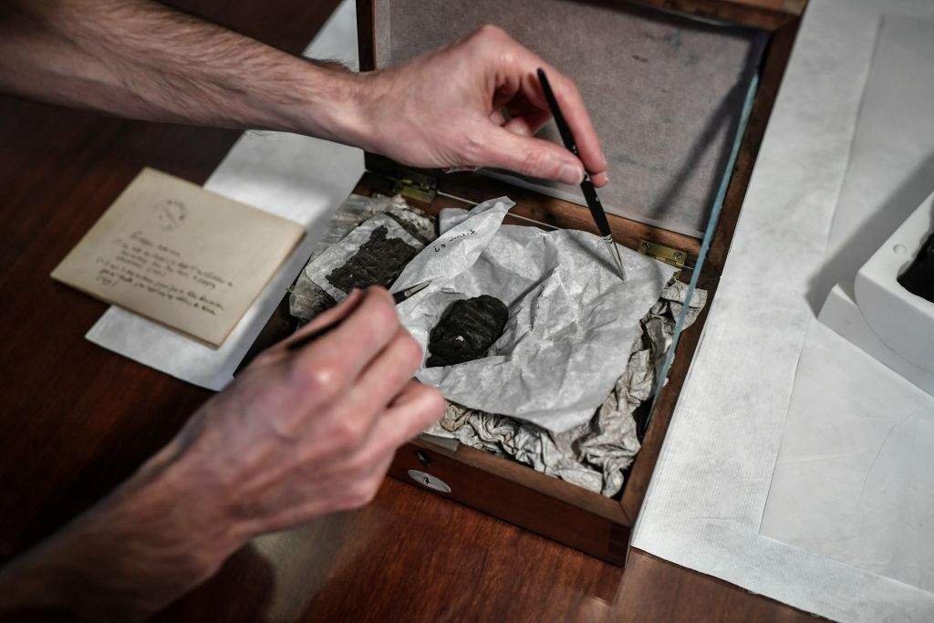 A scientist shows boxes with remains of Herculanum papyrus displayed at the 'Institut de France' in Paris, on September 26, 2019.