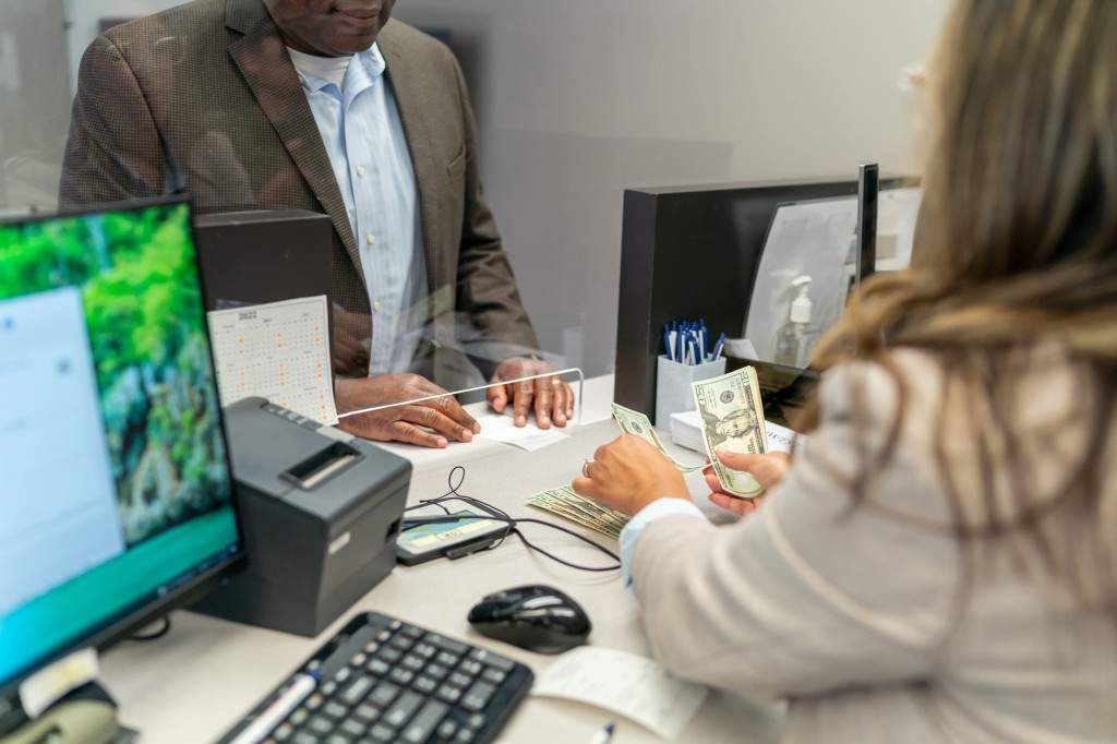 A file photo of a bank teller counting US currency for a customer.